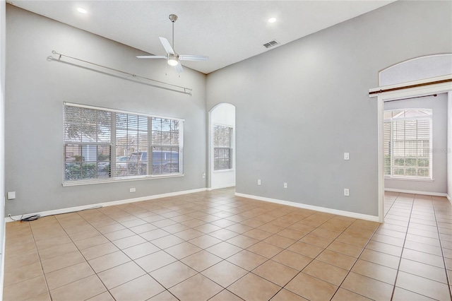 spare room with arched walkways, ceiling fan, light tile patterned floors, and visible vents