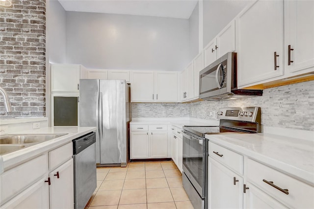 kitchen with light tile patterned floors, stainless steel appliances, tasteful backsplash, light countertops, and white cabinetry