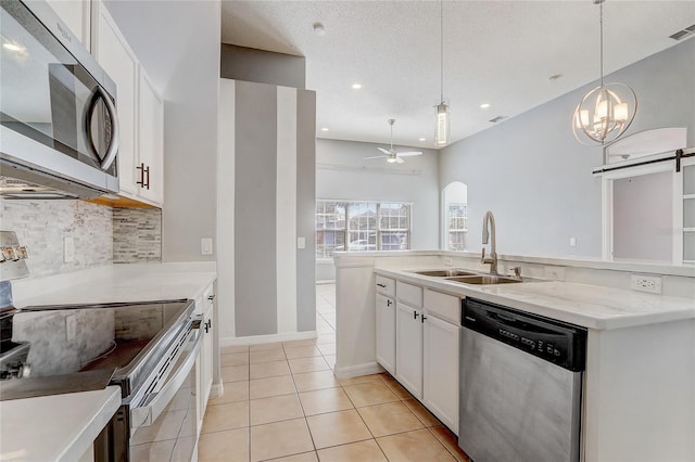 kitchen featuring light tile patterned floors, white cabinets, a sink, stainless steel appliances, and backsplash