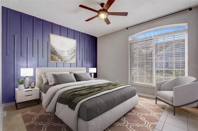 bedroom with light tile patterned flooring, ceiling fan, a textured ceiling, and baseboards