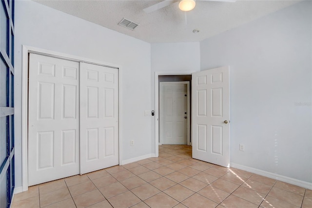 unfurnished bedroom with a closet, visible vents, light tile patterned flooring, a textured ceiling, and baseboards