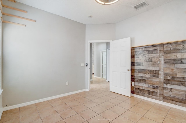 empty room with light tile patterned floors, baseboards, and visible vents