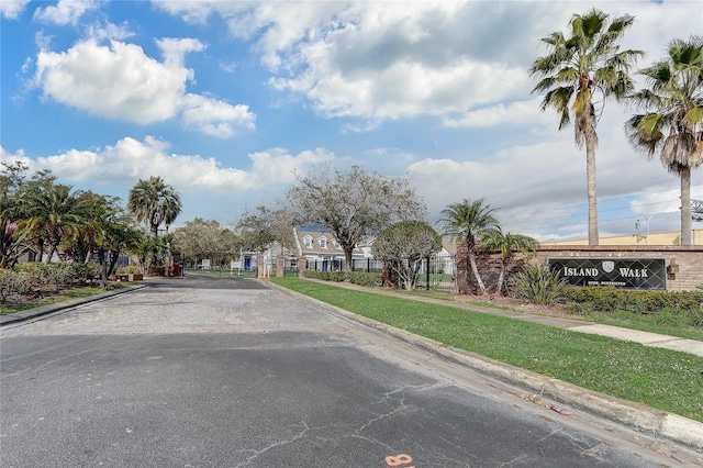 view of street with sidewalks, a gate, a gated entry, and curbs