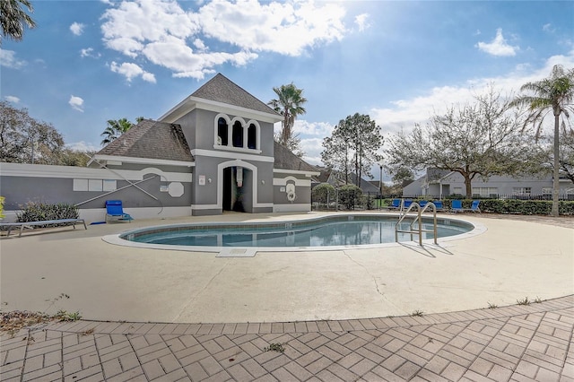 pool with a patio area and fence