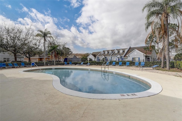 community pool featuring a residential view, fence, and a patio