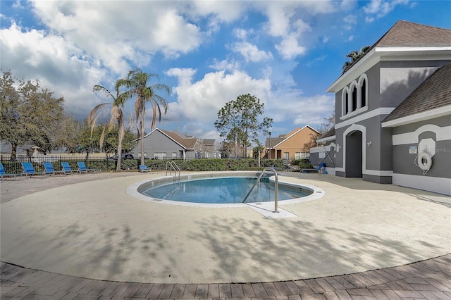 community pool with a residential view, a patio area, and fence