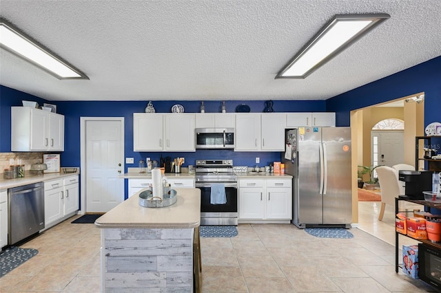 kitchen featuring light tile patterned floors, light countertops, appliances with stainless steel finishes, and white cabinets