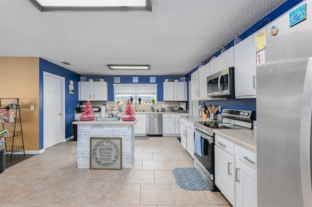 kitchen with a sink, stainless steel appliances, light countertops, and white cabinetry