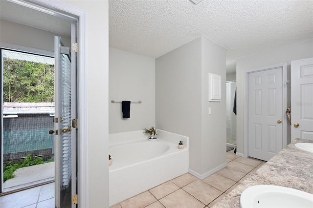 full bath with a stall shower, a garden tub, tile patterned flooring, a textured ceiling, and a sink