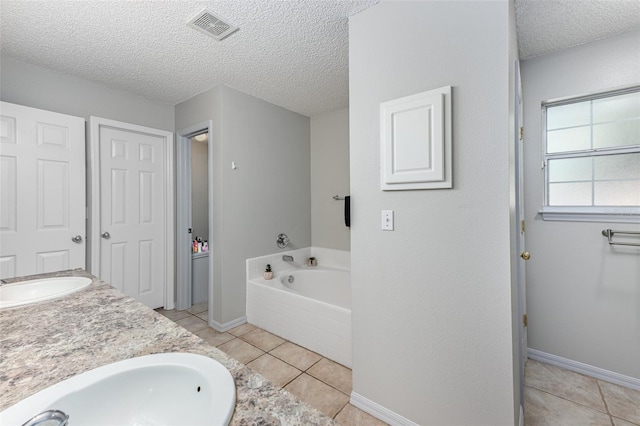 full bathroom featuring a garden tub, visible vents, a sink, a textured ceiling, and tile patterned flooring