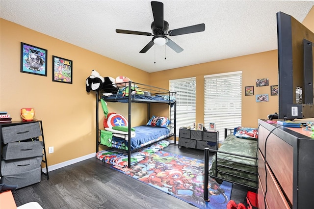 bedroom with a ceiling fan, a textured ceiling, baseboards, and wood finished floors