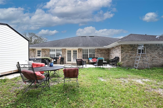 rear view of property with french doors, a patio, roof with shingles, a yard, and brick siding