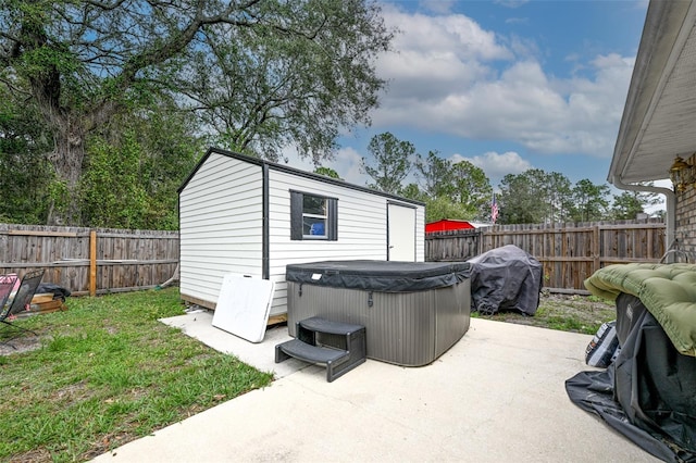 exterior space featuring a hot tub, a fenced backyard, a grill, and an outdoor structure