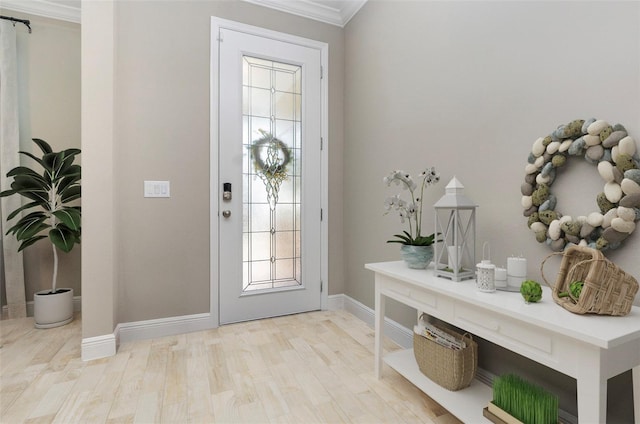 foyer featuring light wood-style floors, ornamental molding, and baseboards