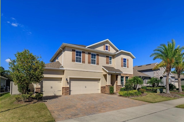 view of front facade with a front yard, decorative driveway, an attached garage, and stucco siding