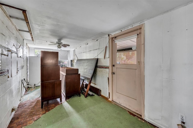 interior space with a ceiling fan and concrete block wall