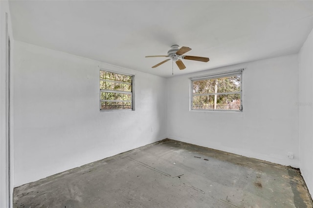 unfurnished room featuring a wealth of natural light, unfinished concrete flooring, and ceiling fan