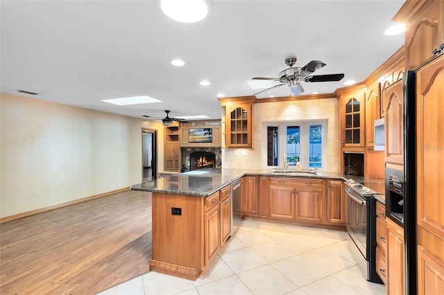 kitchen featuring a skylight, electric range, stainless steel dishwasher, white microwave, and glass insert cabinets