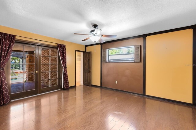 unfurnished room with french doors, a textured ceiling, baseboards, and wood finished floors