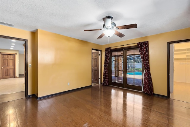 empty room featuring french doors, visible vents, a textured ceiling, wood finished floors, and baseboards