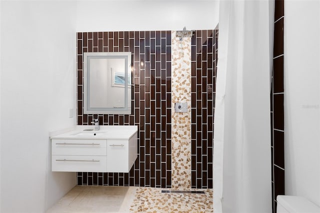 full bathroom with a tile shower, vanity, and toilet