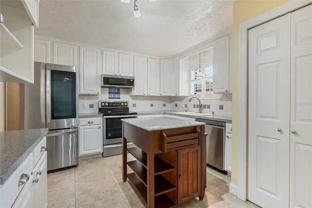 kitchen featuring a sink, open shelves, backsplash, white cabinetry, and appliances with stainless steel finishes