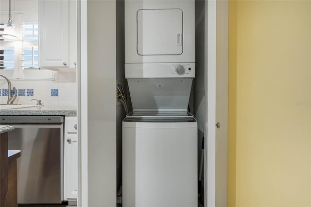 washroom with a sink, stacked washer / drying machine, and laundry area