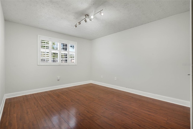 empty room featuring baseboards, a textured ceiling, and dark wood-style flooring