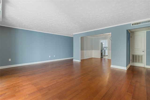 empty room featuring hardwood / wood-style flooring, crown molding, visible vents, and a textured ceiling