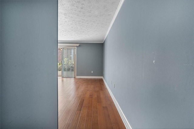 corridor with crown molding, wood finished floors, baseboards, and a textured ceiling