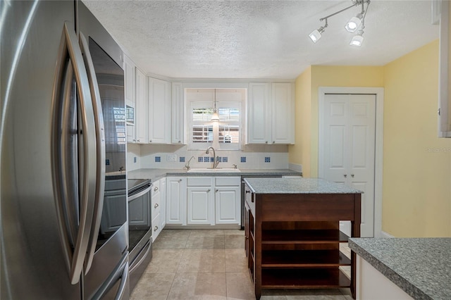 kitchen featuring tasteful backsplash, open shelves, white cabinets, stainless steel appliances, and a sink