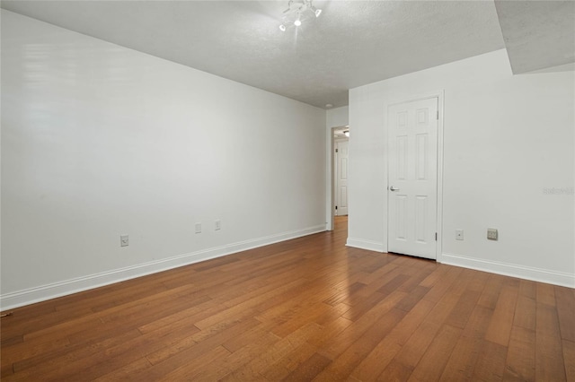 spare room featuring baseboards, a textured ceiling, and hardwood / wood-style flooring