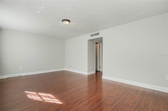 unfurnished room with visible vents, baseboards, a textured ceiling, and dark wood-style floors