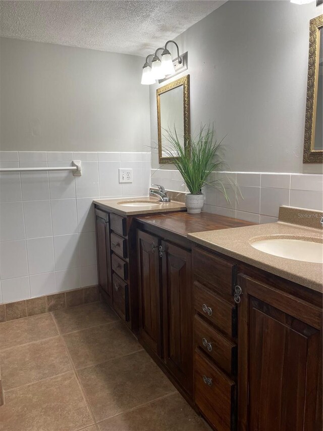 4214 Lake Underhill Rd Unit A, Orlando, FL 32803 - bathroom featuring tile walls, a textured ceiling, double vanity, tile patterned flooring, and a wainscoted wall
