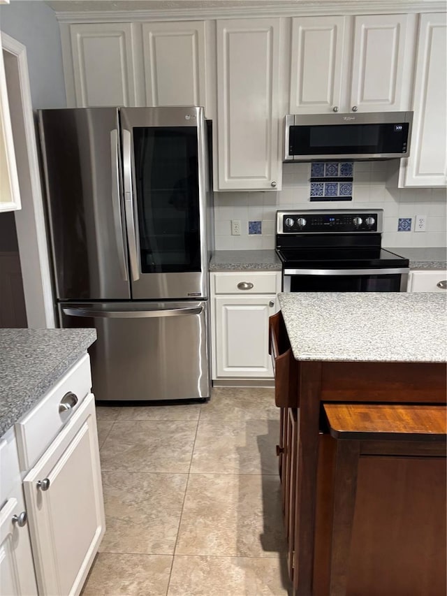 4214 Lake Underhill Rd Unit A, Orlando, FL 32803 - kitchen featuring stainless steel appliances, decorative backsplash, white cabinetry, and light stone counters