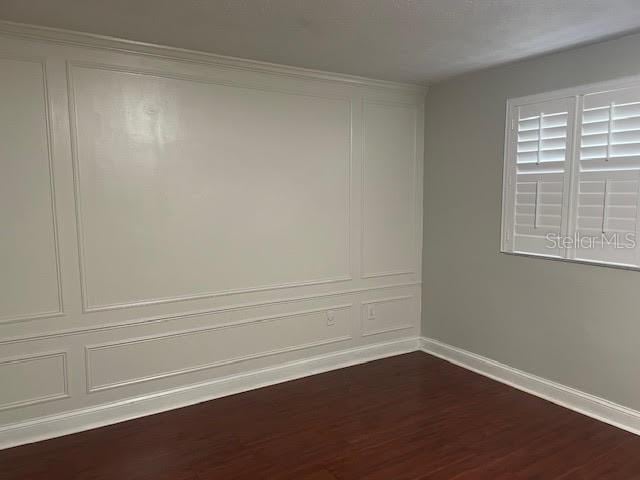 4214 Lake Underhill Rd Unit A, Orlando, FL 32803 - spare room with a decorative wall, dark wood-style flooring, and baseboards