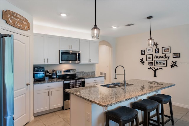 kitchen featuring stainless steel appliances, arched walkways, a sink, and a breakfast bar