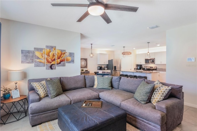 living area featuring light tile patterned floors, baseboards, visible vents, and a ceiling fan