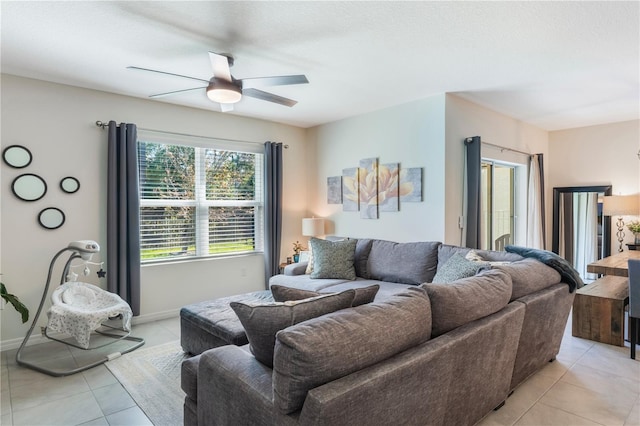 living area with light tile patterned floors, baseboards, and a ceiling fan