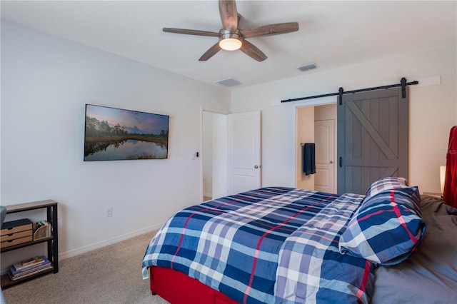 carpeted bedroom featuring ceiling fan, a barn door, visible vents, and baseboards