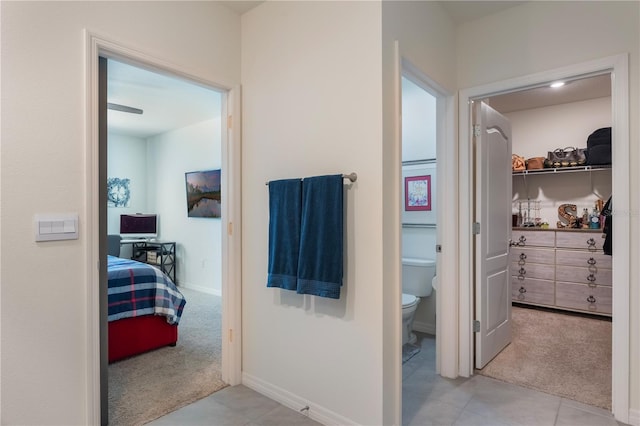 ensuite bathroom with baseboards, toilet, ensuite bath, tile patterned floors, and a spacious closet