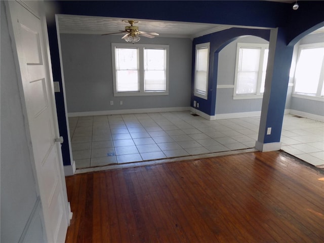 interior space with arched walkways, ceiling fan, baseboards, and wood finished floors