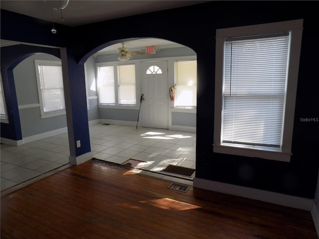 entrance foyer with arched walkways, visible vents, a ceiling fan, tile patterned flooring, and baseboards