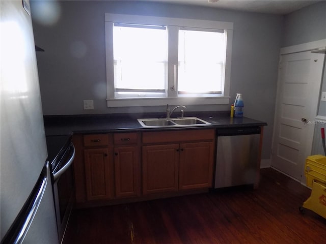 kitchen featuring dark countertops, appliances with stainless steel finishes, dark wood finished floors, and a sink