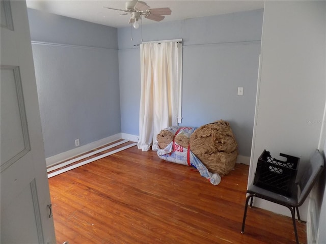 living area featuring a ceiling fan, baseboards, and wood finished floors