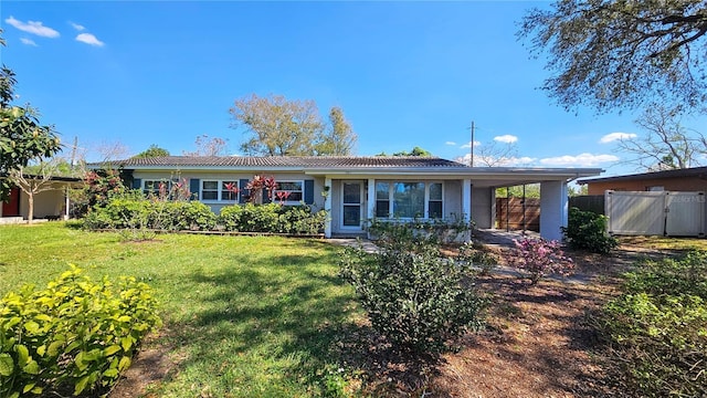 ranch-style house with a carport, fence, and a front lawn