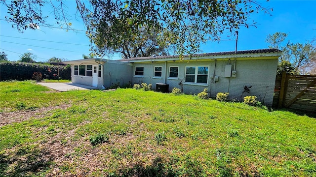 rear view of property featuring a yard, brick siding, a patio area, and fence