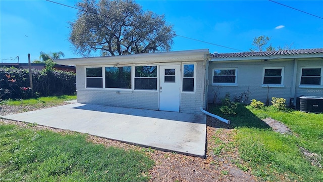 exterior space featuring cooling unit, brick siding, a patio, and a front lawn