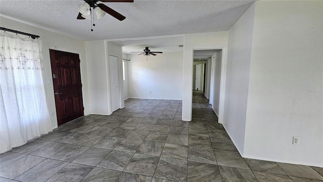 spare room with baseboards, a ceiling fan, and a textured ceiling