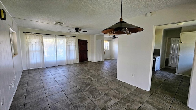 empty room featuring a ceiling fan, visible vents, and a textured ceiling